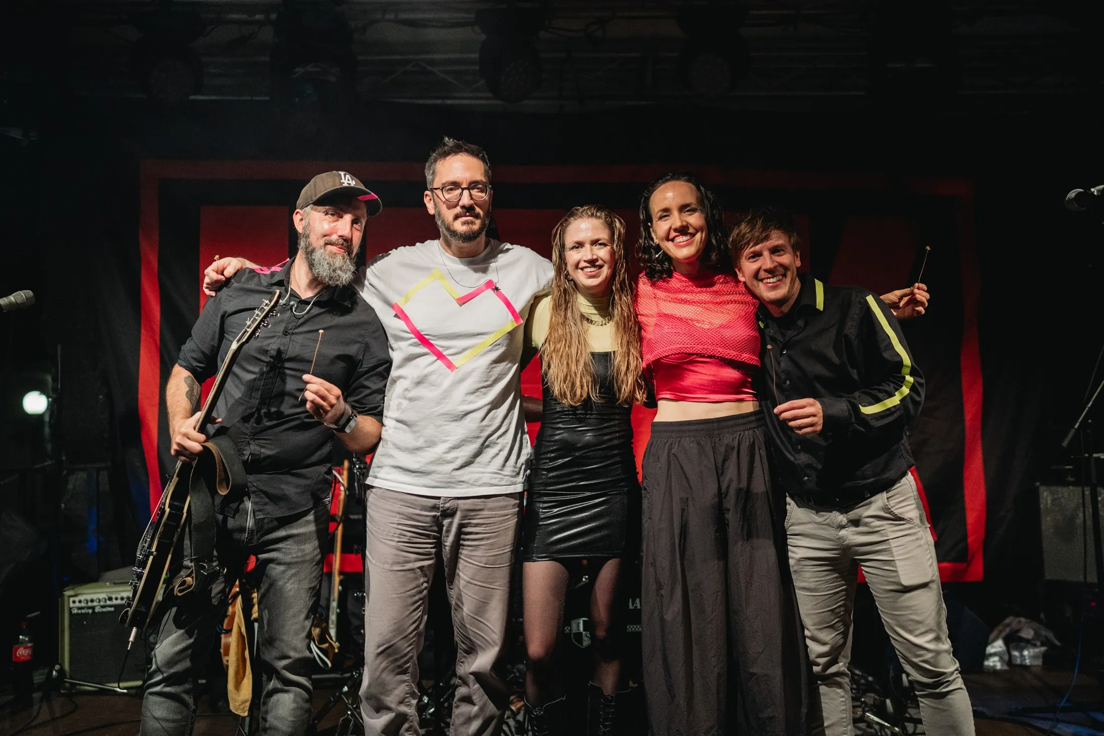 Die fünf Bandmitglieder Arm in Arm auf der Bühne nach einem Konzert