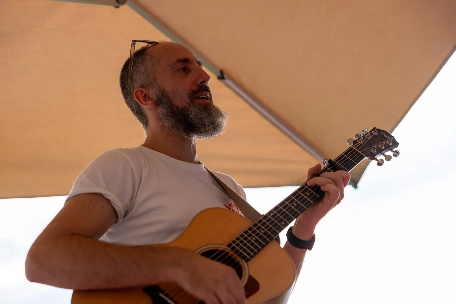 Steffen mit Akustikgitarre unter dem Sonnenschirm